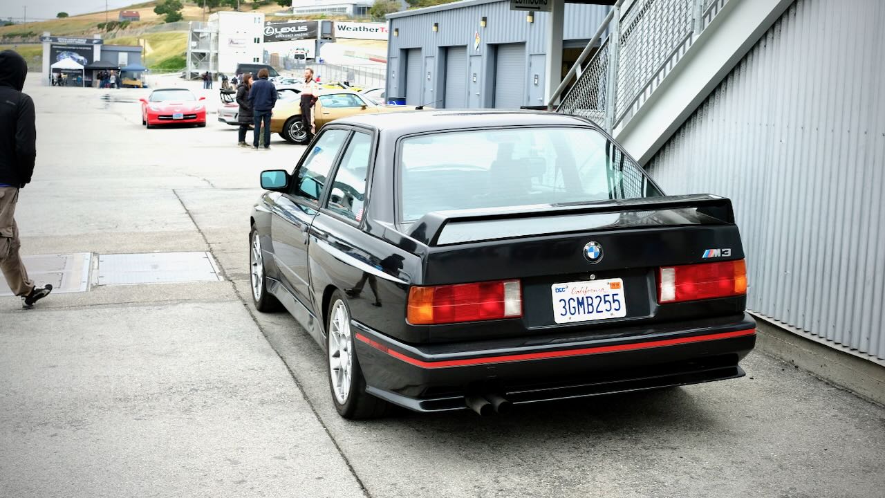 A black E30 M3 parked at a race track