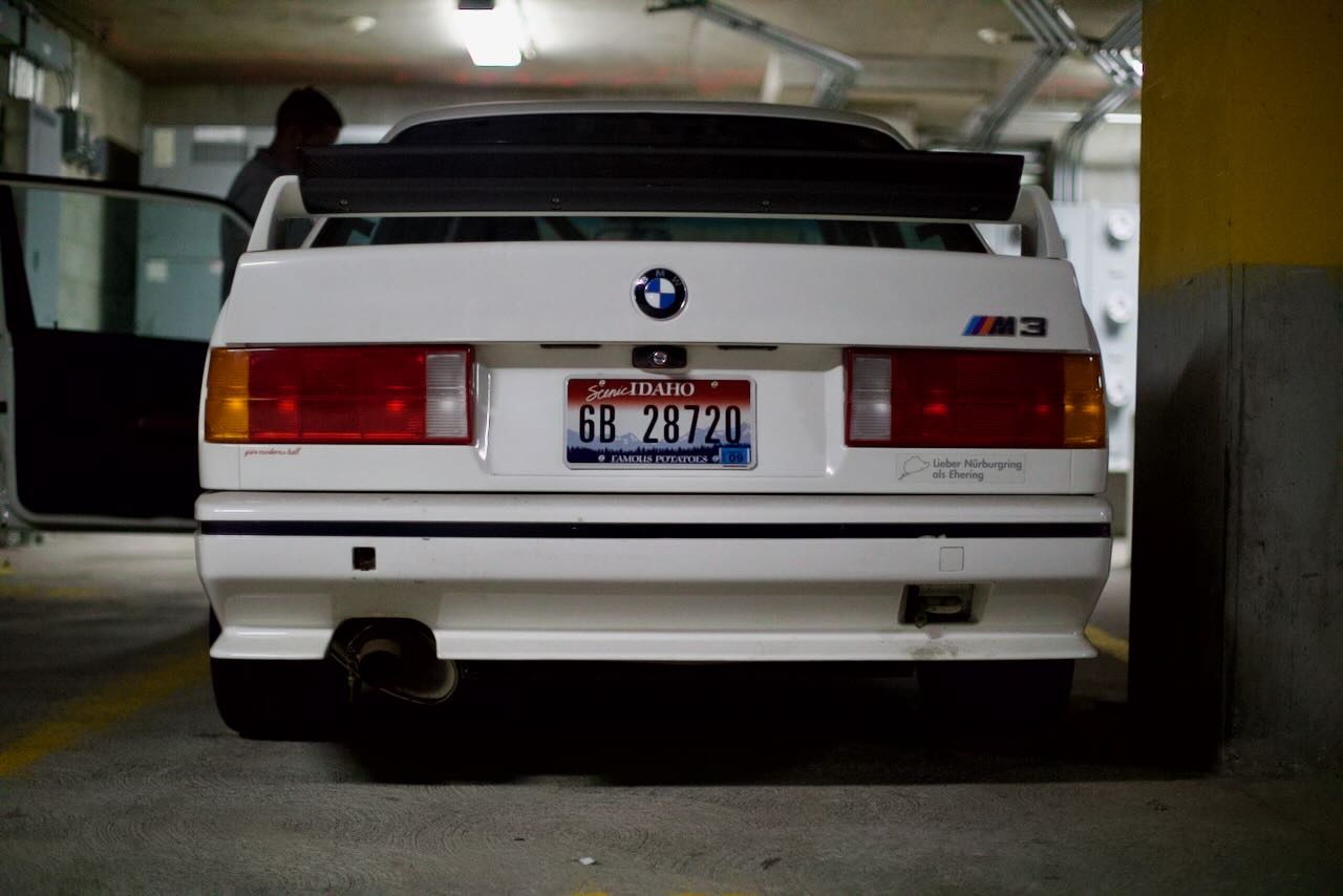 A black E30 M3 parked at a race track